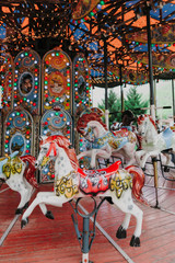 Multi-colored children's carousel with horses marry-go-round at the summer fair. Vertical image.