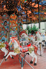 Multi-colored children's carousel with horses marry-go-round at the summer fair. Vertical image.