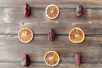 Orange chips, dried orange slices, and date fruits on wooden backgrond. Horizontal image. Top view, flat lay. Copy space