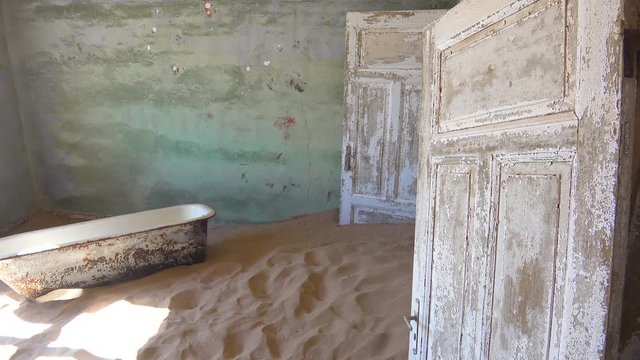 Sand and a bath tub fills an abandoned building in the gem mining ghost town of Kolmanskop, Namibia.