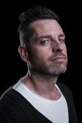 Obraz premium Side studio portrait of a caucasian man looking at the camera. Isolated on black background. Vertical. Closeup.