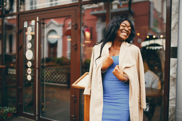 Elegant black woman standing in a autumn city. Businesswoman in a blue dress