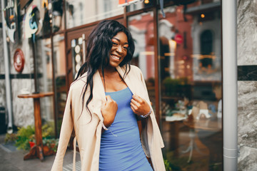 Elegant black woman standing in a autumn city. Businesswoman in a blue dress