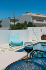 a glass of white wine on the table by the pool