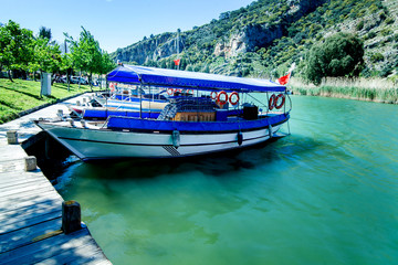 Tourist boat moored on the banks of the green river on the background of beautiful scenery