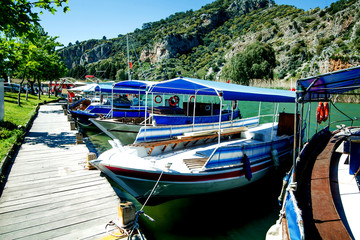 Tourist boat moored on the banks of the green river on the background of beautiful scenery