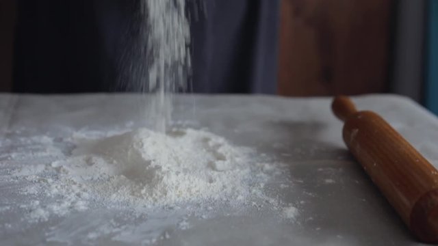 old woman hands pours flour on the table, kneading a dough on bread or dumplings, Ukrainian tradition