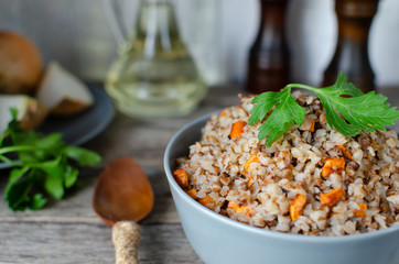 Buckwheat porridge with carrots and parsley in blue plate. On background of Golden onions,green parsley and salt and pepper mills.