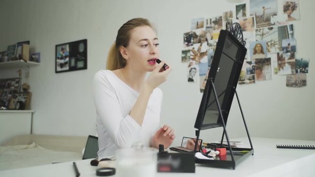 Woman applying lipstick. Young model putting on some makeup, using lipstick to color hel lips