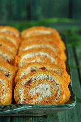 Sliced carrot roulade on a platter on a wooden background