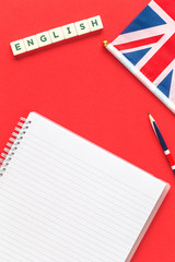 Word English on a red desk with a pencil and a blank notebook and british english union jack flag....