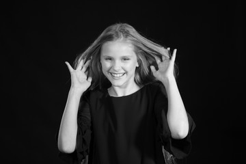 Portrait of a blonde girl with long hair on a black background. Emotional portrait.The girl shows different emotions on the face. Plays with long hair. Black and white portrait.