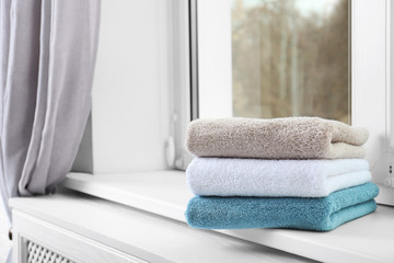 Folded clean towels on window sill. Space for text