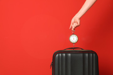 Woman weighing suitcase against color background, closeup. Space for text