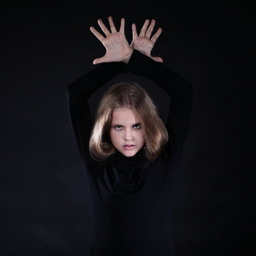Portrait of a blonde girl with long hair on a black background. Emotional portrait.The girl shows different emotions on the face. Plays with long hair.