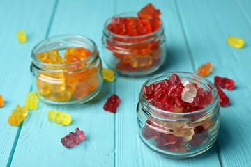 Fototapeta na wymiar Three glass jars with delicious jelly bears on wooden table