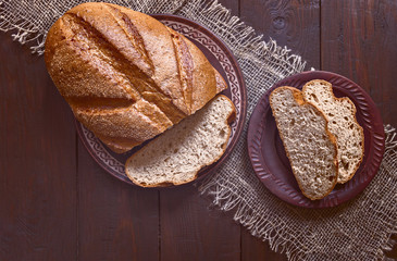 a fresh loaf of bread and slices of bread on the table. wooden simple background with crispy fresh bread.