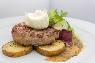 chopped beef cutlet on a pillow of potatoes with lettuce, poached egg and spicy gravy