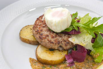 chopped beef cutlet on a pillow of potatoes with lettuce, poached egg and spicy gravy