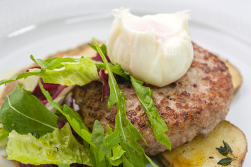chopped beef cutlet on a pillow of potatoes with lettuce, poached egg and spicy gravy