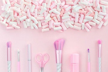 Feminine nail polish accessories and unicorn makeup brushes on pink background with trendy pastel marshmallows. Flat lay with copy space, beauty and cosmetics blogger or birthday card concept