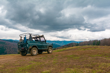 Extreme tourist trip to the top of the mountain on the dirt and stones on a special off-road Jeep to see the beauty of the mountains and forests on the horizon on top of the world