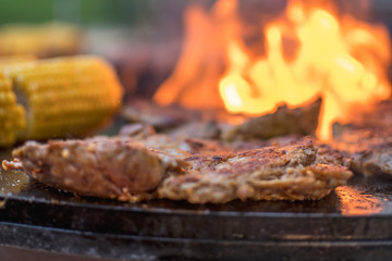 fresh raw steak with corn an a open fire grill