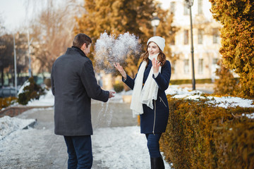 Pretty couple walking in a winter park. Man and woman have fun with snow