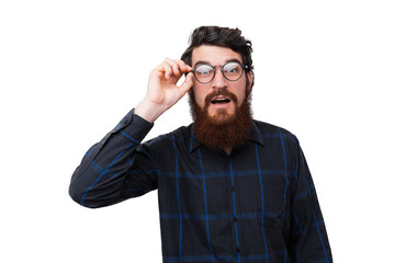 Fototapeta premium Photo of surprised bearded man, touching his glasses, and looking at camera