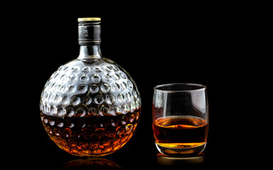 Glass of scotch whiskey and old decanter isolated on a black background