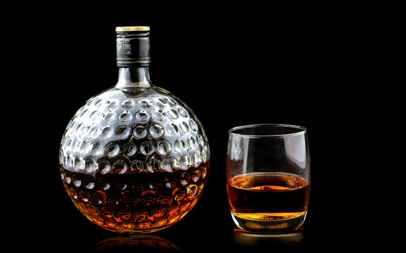 Glass Of Scotch Whiskey And Old Decanter Isolated On A Black Background