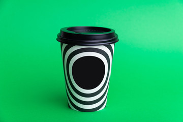 Photo of a black white take away cup over green background