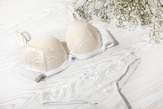 White female underwear on white wooden background. Bra and panty, decorated with decorative flowers - Fashion and stillife photo - Image