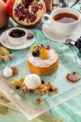Vanilla cake with whole poached pears and cup of tea on blue wooden table