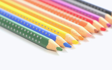  Colored pencils for the artist. Multicolored sticks of polka dot wood on a white background.