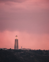 telephoto of Sanctuary of Christ the King (Santuario de Cristo Rei) in a dramatic sunset is Lisbon, Portugal