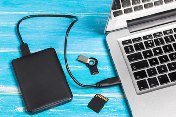 Top view silver laptop / notebook with external hard drive disk HDD and SD card on wooden table with copy space