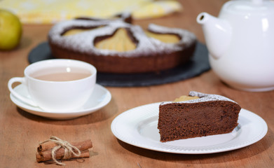 Piece of homemade chocolate cake with pears on a rustic background