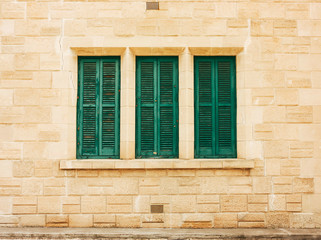 Fototapeta na wymiar Green shutters on the old wall, made of stone