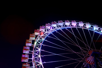Part of ferris wheel with blue lighting at night.
