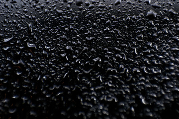oil and water drops on black glass surface abstract background