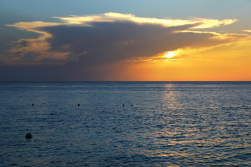 Colorful empty seascape with shiny sea over cloudy sky and sun during sunset in Cozumel, Mexico