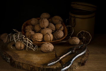 A brown plate with nuts on dark wood .Walnuts on dark background. Low-key image