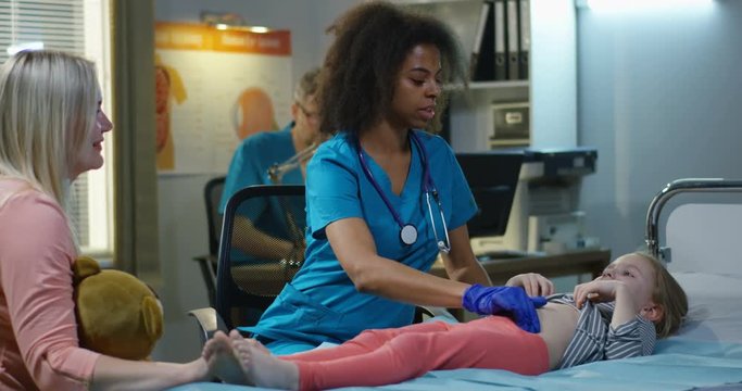 Female doctor examining girls abdomen