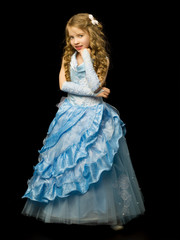 A little girl in a long, elegant dress of a princess on a black 
