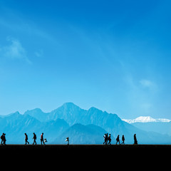 Fototapeta premium Silhouetted people walking on street over blue sky