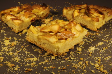 Pieces of apple pie on a grey background with crumbs