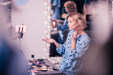 Woman sitting at the table with cosmetics while filming blog