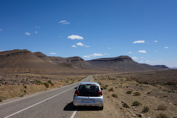 Road trip with a compact car through the desert countryside of Morocco, on the way to Merzouga