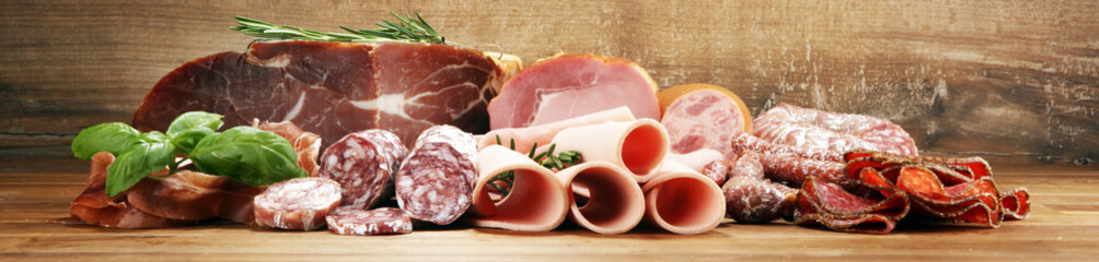 cold meat assortment with delicious salami and  fresh herbs . Variety of meat products including...